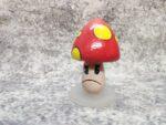 Fýlusveppur. Úr Cuphead tölvuleiknum. Hattur er með sterkum gormi og fjaðrar eins og bobblehead.